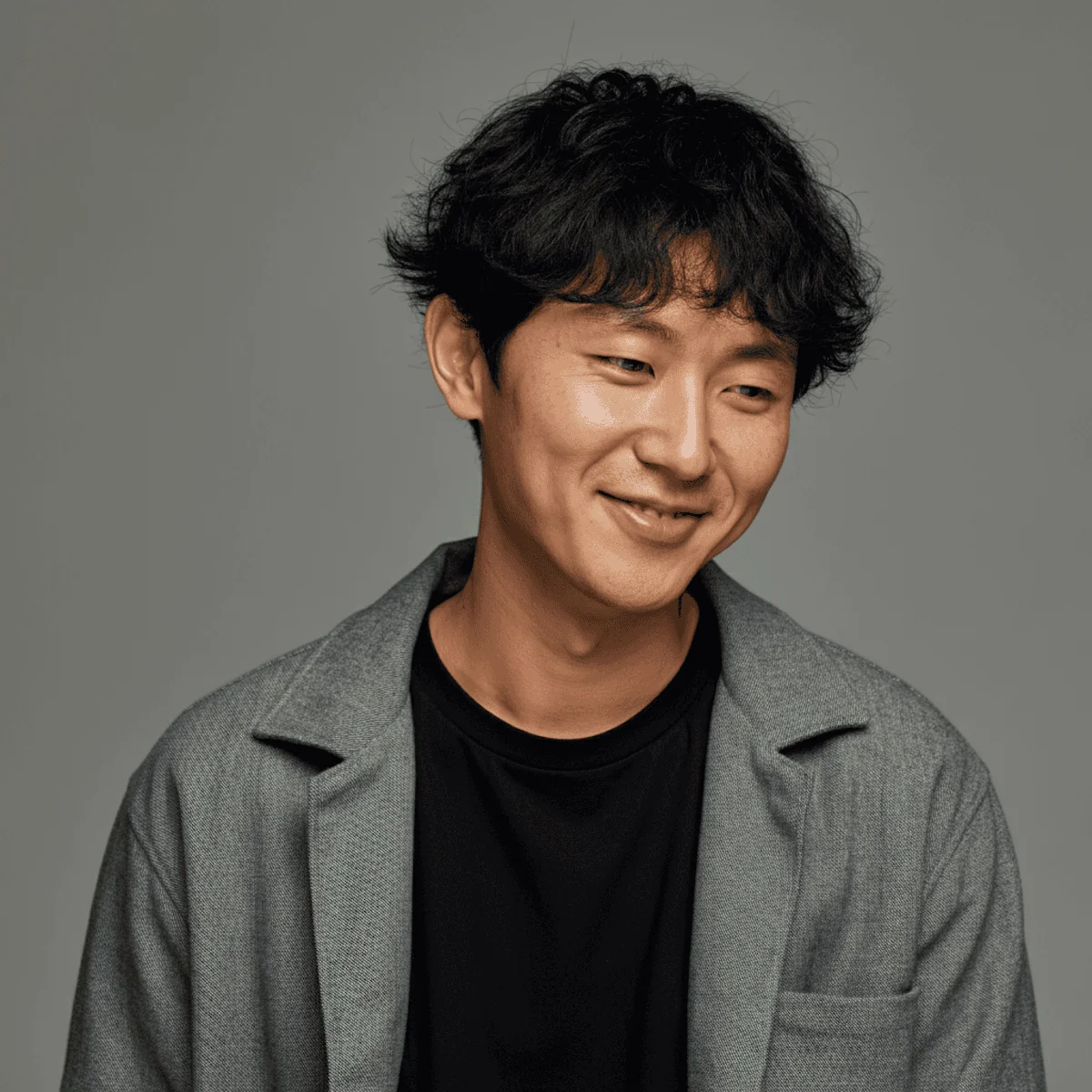 An asian man smiling looking down
