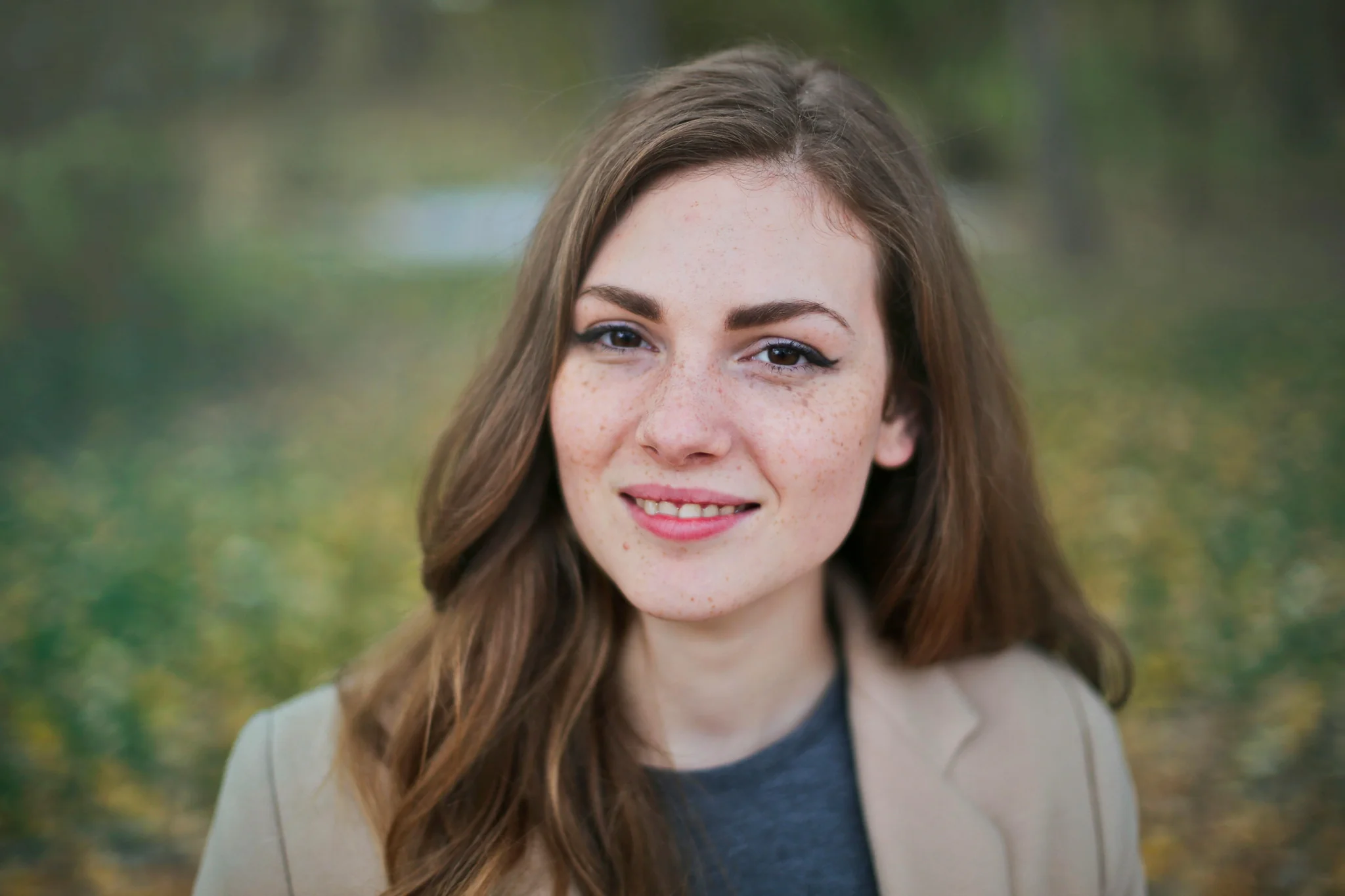 smiling woman standing near green tree